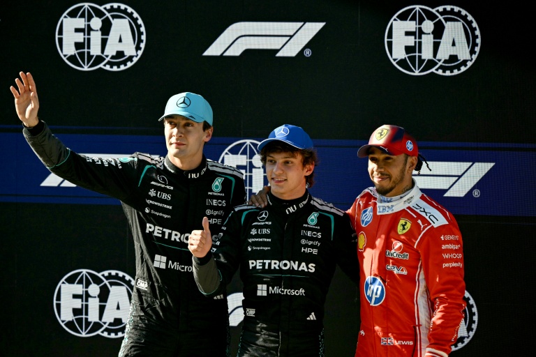 Le pilote italien de Mercedes, Kimi Antonelli (au centre), célèbre sa pole position aux côtés du pilote britannique de Mercedes George Russell (à gauche), deuxième, et du pilote britannique de Ferrari Lewis Hamilton, troisième, à l'issue de la séance de qualifications du GP de Chine de F1, à Shanghai, le 14 mars 2026