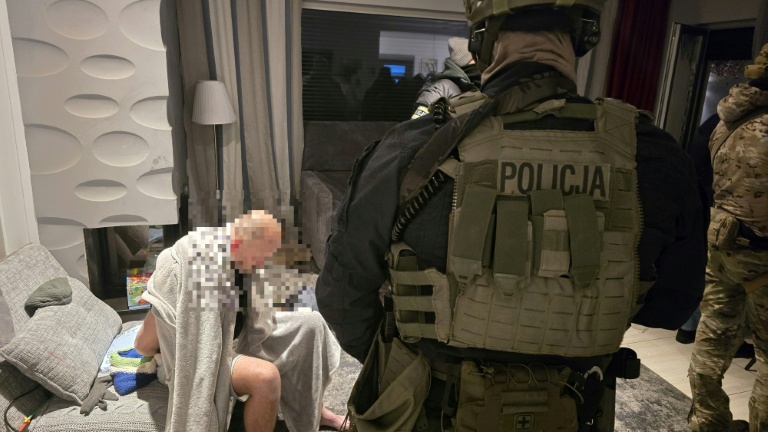 Photo prise le 16 janvier 2026 dans un lieu non précisé en Pologne et publiée le 21 janvier montrant des policiers polonais avec un homme arrêté (g), soupçonné d'être impliqué dans la production de drogue, lors de la perquisition d'un appartement