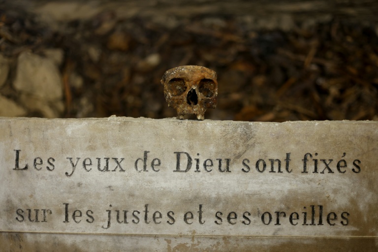 Des crânes et des ossements humains alignés contre un mur des catacombes de Paris, le 24 mars 2026
