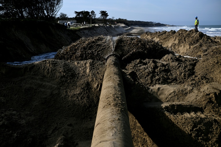 Un mélange de sable et d'eau est expulsé d'un tuyau dans le cadre d'une expérimentation de lutte contre l'érosion marine, à Soulac-sur-Mer, en Gironde, le 10 avril 2026