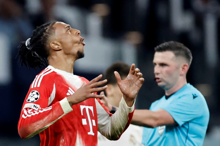 Le milieu de terrain français du Bayern Munich, Michael Olise (g.), et l'arbitre anglais Michael Olivier (d.), lors du match aller des quarts de finale de la Ligue des champions opposant le Real Madrid au Bayern Munich, au stade Santiago Bernabeu, le 7 avril 2026