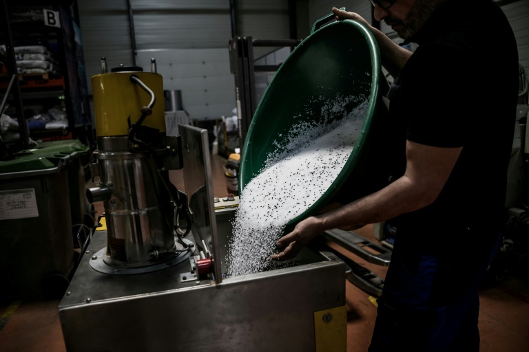 Un employé de l'usine Francia, spécialisée dans l'injection de plastique, déverse des granulés de plastique dans une machine, le 16 avril 2026 à Bellignat, dans l'Ain