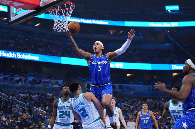 Paolo Banchero (c) tente un panier malgré la défense de Grant Williams lors du match de play-in NBA du Magic d'Orlando contre les Charlotte Hornets, le 17 avril 2026 à Orlando