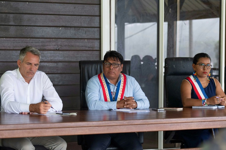 Photo diffusée le 11 mai 2026 par les Forces armées françaises montrant le préfet de Guyane, Antoine Poussier (g), le maire de Camopi, Laurent Yawalou (c) et la première adjointe Mathilde Tatou, lors d'une réunion à Camopi, où les habitants manifestent contre les passages de frontière des orpailleurs illégaux, en Guyane