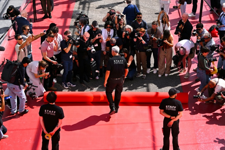 Un employé déroule le tapis rouge devant le Palais des Festivals à Cannes le 12 mai 2026