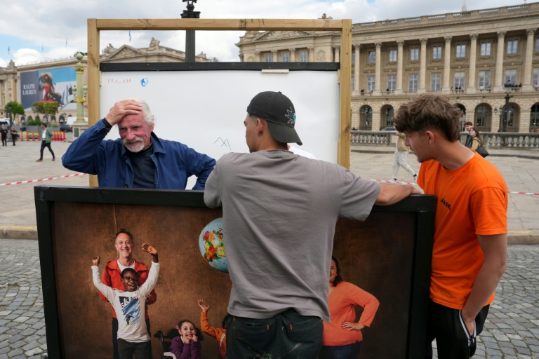 Le photographe Yann Arthus-Bertrand (G) avec des volontaires ayant aidé à la remise en place de l'exposition photos en plein air sur la place de la Concorde à Paris, le 7 mai 2026