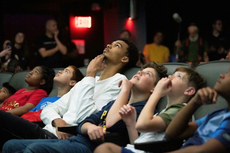 Victor Wembanyama regarde une vidéo entouré d'enfants lors de son passage au Planétarium de San Antonio, le 11 mai 2024