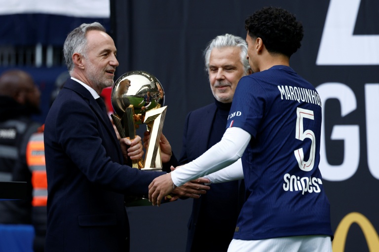 Le maire de Paris, Emmanuel Grégoire (g.), et le président de la Ligue de football professionnel, Vincent Labrune (c.), remettent le trophée de champion de Ligue 1 au défenseur central brésilien du Paris Saint-Germain, Marquinhos, avant le match de L1 opposant le Paris FC au PSG, au Stade Jean-Bouin, à Paris, le 17 mai 2026