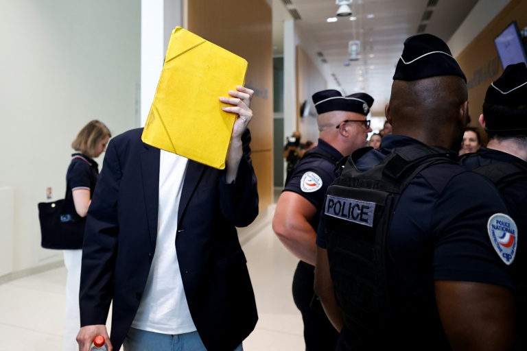 David G., animateur périscolaire, se cache le visage avec un dossier à son arrivée au tribunal où il doit être jugé pour agressions sexuelles sur neuf enfants, le 26 mai 2026