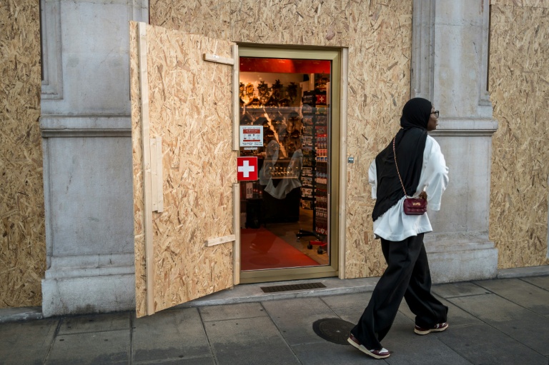 Une touriste marche devant un magasin de souvenir protégé par des panneaux de contreplaqué avant les manifestations anti-G7 prévues en marge du sommet à Evian, à Génève le 12 juin 2026