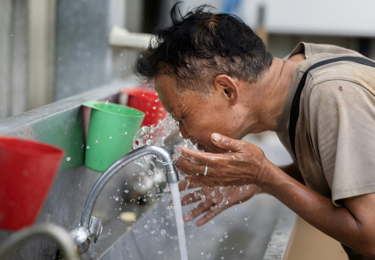 Un employé s'asperge le visage d'eau alors qu'il travaille dans une serre de tomates à Taulé, dans l'ouest de la France, le 25 juin 2026