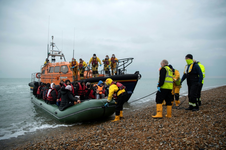 Des migrants sont aidés à débarquer d'un canot de sauvetage de la RNLI (Royal National Lifeboat Institution) sur une plage de Dungeness, en Angleterre, le 24 novembre 2021, après avoir été secourus alors qu'ils traversaient la Manche
