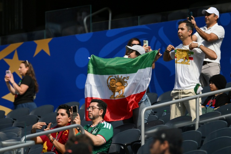Des supporters iraniens exhibent un drapeau et un t-shirt arborant le lion et le soleil, symboles du drapeau iranien avant la révolution de 1979, avant le match du Mondial Iran-Nouvelle-Zélande au Los Angeles Stadium d'Inglewood, le 15 juin 2026