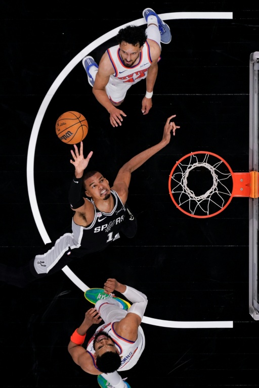Le pivot français des San Antonio Spurs Victor Wembanyama tire au panier entre Karl-Anthony Towns (en bas) et Landry Shamet des New York Knicks lors du match N.1 de la finale NBA le 3 juin 2026 à San Antonio (Texas)