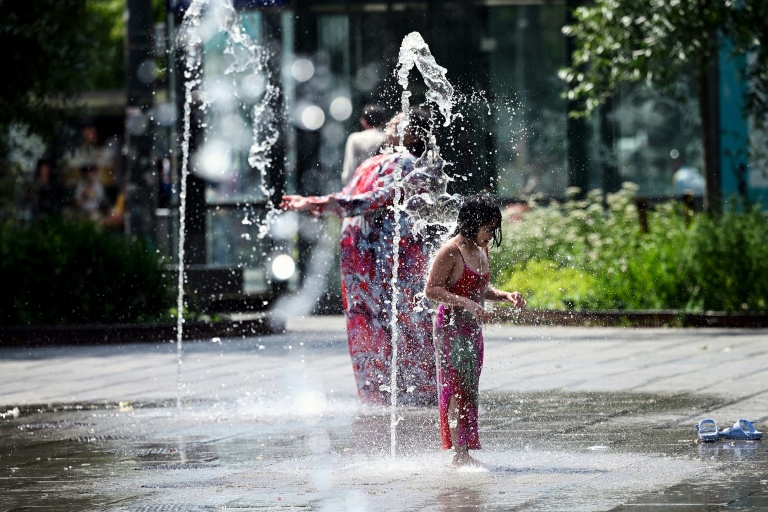 Un enfant se rafraîchit dans un parc à Bruxelles le 19 juin 2026