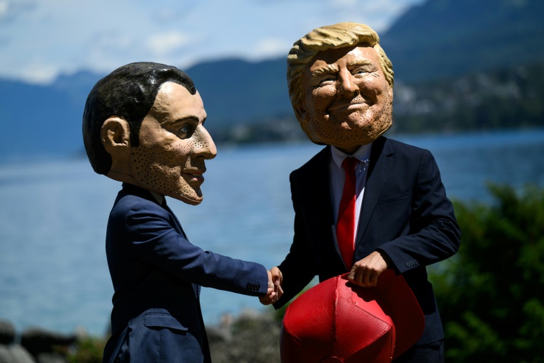 Des manifestants affublés de grosses têtes caricaturant le président français Emmanuel Macron et le président américain Donald Trump, posent lors d'un événement organisé par l'ONG Oxfam, à Publier, près d'Evian, dans l'est de la France, le 14 juin 2026
