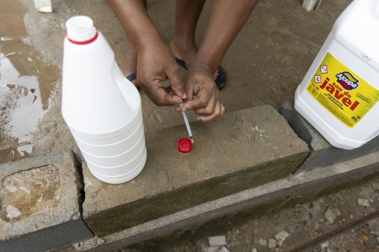 Un conseiller de la Croix-Rouge s'apprête à ajouter une dose d'eau de Javel à de l'eau pour la rendre potable, le 6 juin 2026 à Savane, un quartier de Matoury, en périphérie de Cayenne