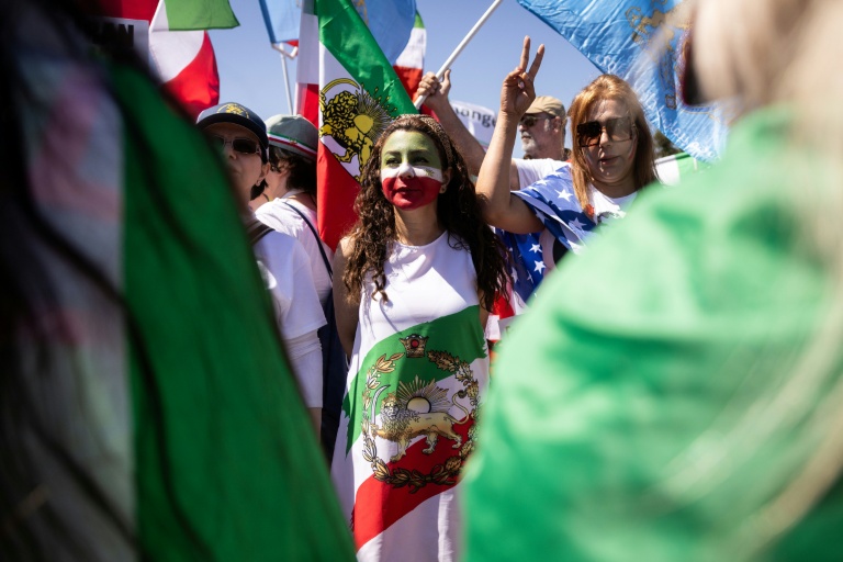 Une manifestante envelopée dans un drapeau utilisé par l'Iran avant la révolution islamique, autour du SoFi Stadium à Inglewood, près de Los Angeles, le 15 juin 2026