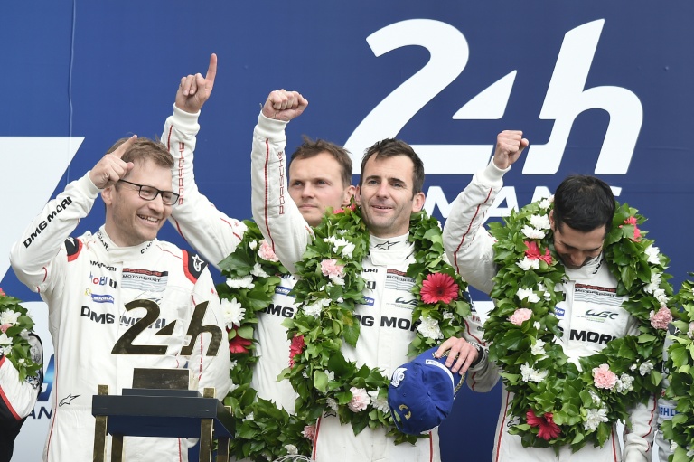 Romain Dumas, casquette bleue en main, célèbre sa victoire aux 24 Heures du Mans sur le podium, aux côtés (de gauche à droite) d'Andreas Seidl, le patron de l'écurie Porsche Motorsport, de Marc Lieb et de Neel Jani, le 19 juin 2016
