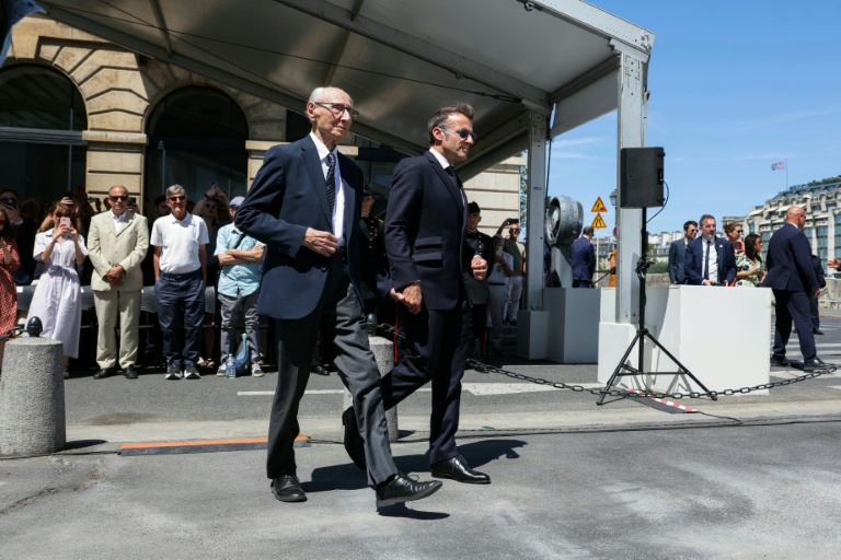 Le président français Emmanuel Macron (D) tient la main de Charles Dreyfus, petit-fils d'Alfred Dreyfus, le 12 juillet 2026, lors de la première journée nationale de commémoration de la reconnaissance de l'innocence du capitaine Dreyfus, officier juif injustement condamné pour haute trahison dans un profond climat antisémite à fin du 19e siècle