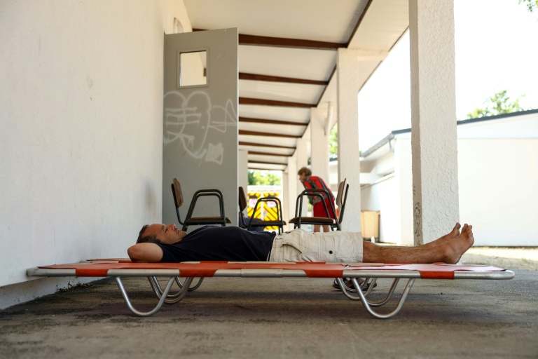 Un homme se repose sur un lit de camp à l'extérieur d'une salle au Porge, en Gironde, ouverte pour les personnes évacuées en raison de l'incendie qui sévit au nord du bassin d'Arcachon, le 23 juillet 2026
