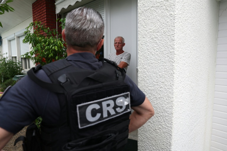 Un CRS discute avec un habitant de la commune de Saint-Médard-en-Jalles, près de Bordeaux, où un ordre d'évacuation a été émis en raison des feux de forêts, le 25 juillet 2026
