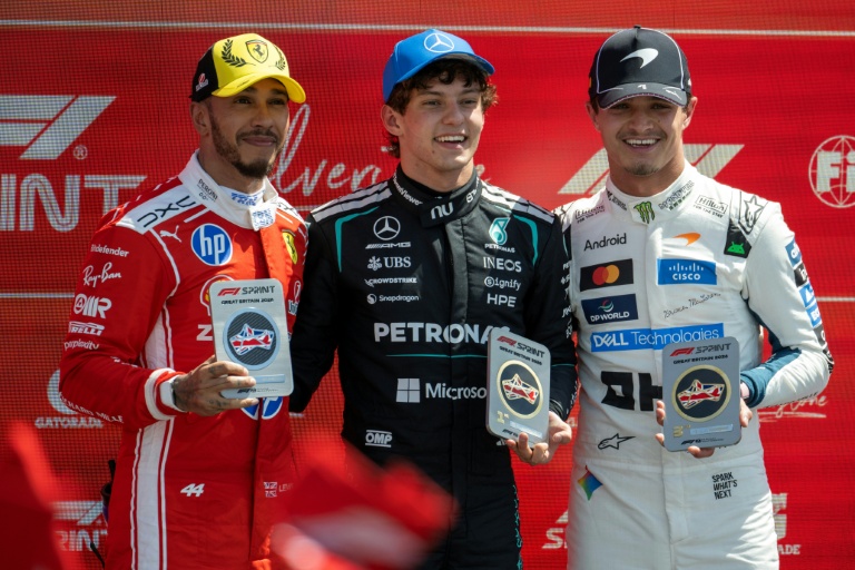 Le jeune Italien Kimi Antonelli, vainqueur de la course sprint du Grand Prix de Grande-Bretagne de Formule 1 (au centre), pose entouré des Britanniques Lewis Hamilton (à gauche) et Lando Norris, respectivement deuxième et troisième, à Silverstone le 4 juillet 2026