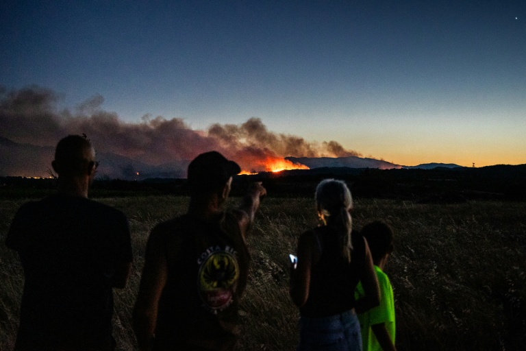 Des habitants observent un incendie de forêt, depuis les abords de Millas, dans les Pyrénées-Orientales, le 5 juillet 2026