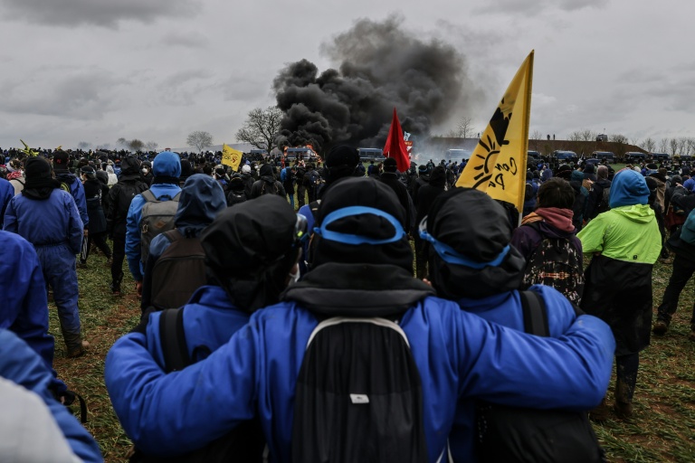 Des manifestants regardent un fourgon de gendarmerie brûler lors de la manifestation contre une 