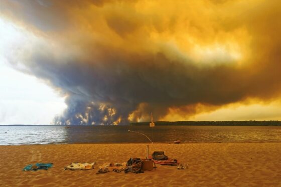 Ciel orange obscurci par des fumées de feux de forêts près d'une plage.
