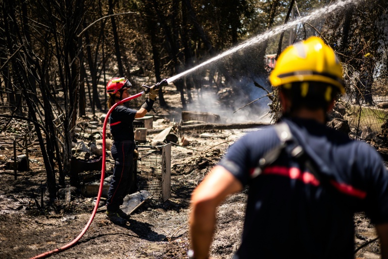 Un pompier lutte à la lance pour empêcher le feu de reprendre à Ille-sur-Têt, près de Perpignon, le 6 juillet 2026 dans les Pyrénées-Orientales