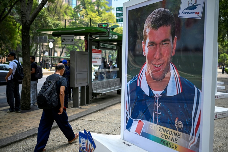 Un homme marche près d'une photo de l'ancien footballeur français Zinedine Zidane, lors d'une exposition consacrée à l'album Panini de la Coupe du monde, sur l'avenue Reforma à Mexico, le 11 mai 2026