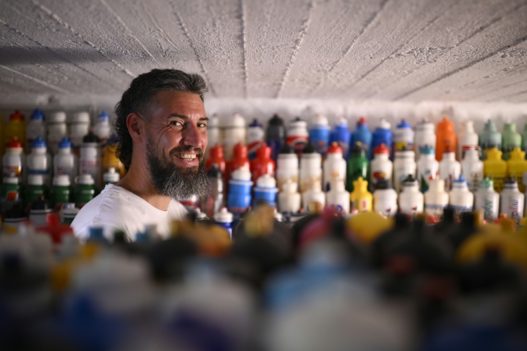 Le fan belge de cyclisme Cédric Raemackers pose devant sa collection de 6.000 bidons de cyclisme récoltés depuis 1992, dans la cave de sa maison à Wanze en Belgique le 22 juin 2026