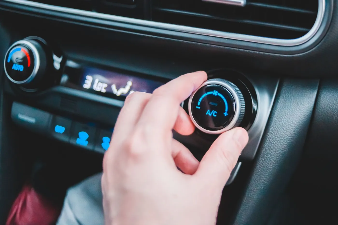 Conducteur réglant la climatisation de sa voiture sur la commande A/C