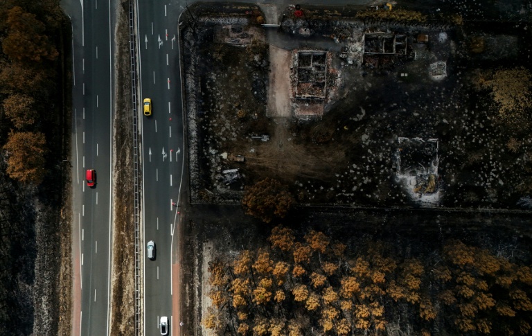 Des voitures circulent sur une route jouxtant des propriétés incendiées, à la suite d'un feu de forêt qui a fait rage en Gironde, à Lanton, le 4 août 2026