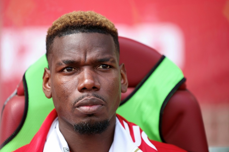 Paul Pogba assis sur le banc de touche avec une expression sérieuse.