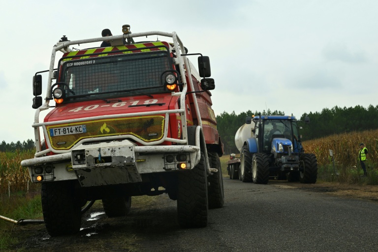 Des pompiers et des agriculteurs remplissent leurs citernes d'eau lors d'un feu de forêt à Luglon, le 16 août 2026 dans les Landes