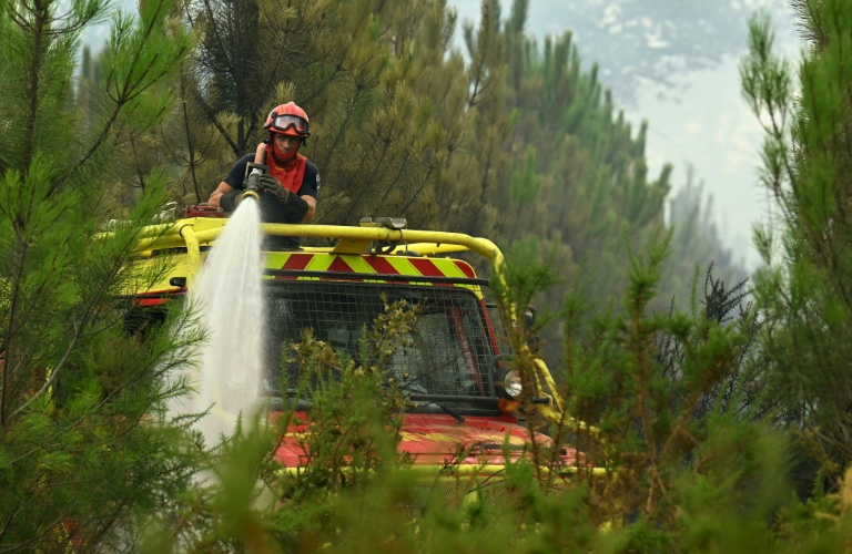 Un pompier arrose des pins pour lutter contre l'incendie en cours dans la forêt des Landes, près de Luglon, le 15 août 2026
