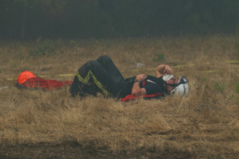 Un pompier est étendu sur l'herbe desséchée au cours d'une intervention contre un feu de forêt près de Lanton, en Gironde, le 29 juillet 2026