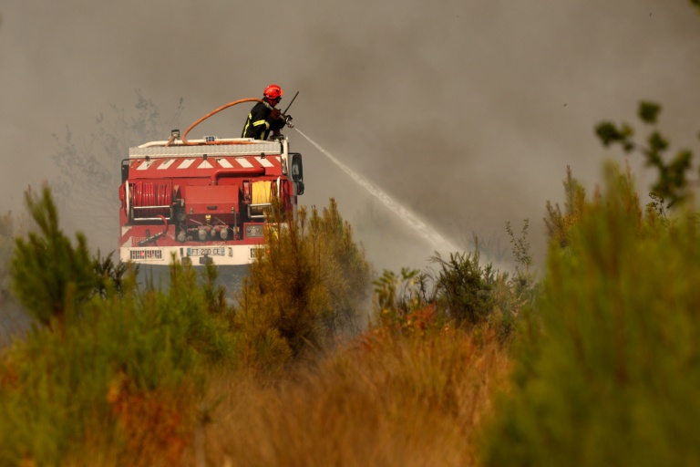 Un pompier arrose de la végétation dans la zone d'un feu de forêt Blagon, à l'ouest de Bordeaux, le 26 juillet 2026