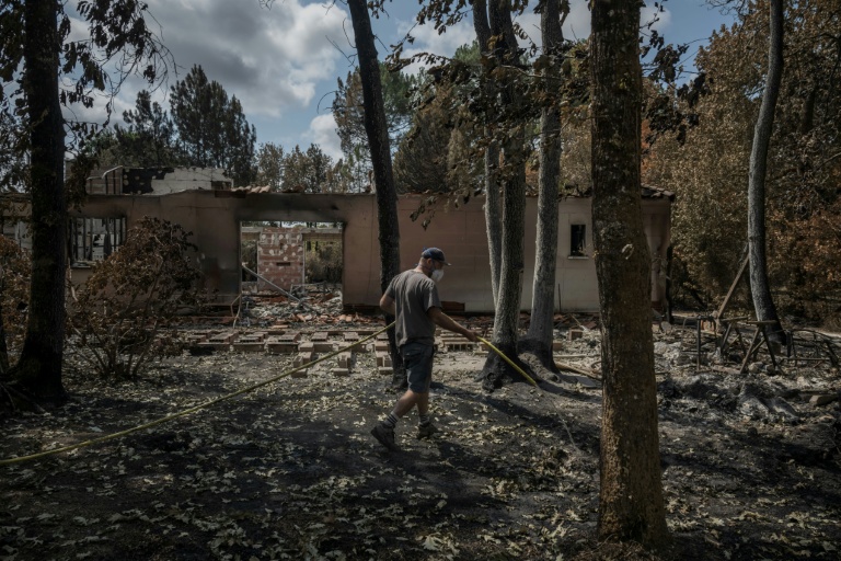 Un habitant éteint des brandons avec un tuyau d'arrosage dans la commune de Le Porge, en Gironde, ravagée par un incendie, le 31 juillet 2026