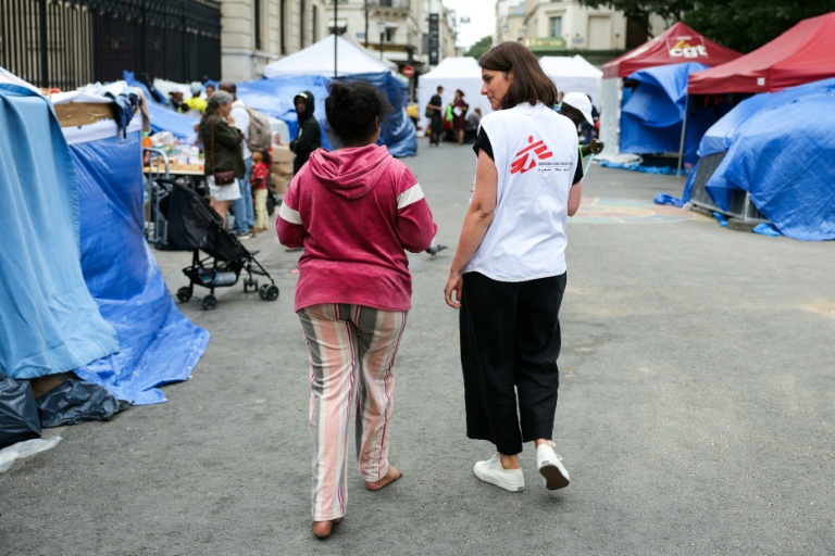 Un membre de Médecins sans frontières parle avec une migrante dans un camp de fortune installé en plein centre de Paris le 21 août 2026