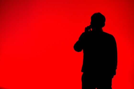Silhouette d'une personne utilisant un téléphone sur fond rouge