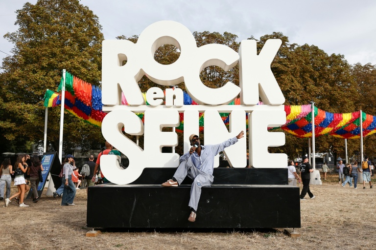 Un festivalier pose devant l'enseigne du festival Rock en Seine à Saint-Cloud dans les Hauts-de-Seine le 26 août 2026