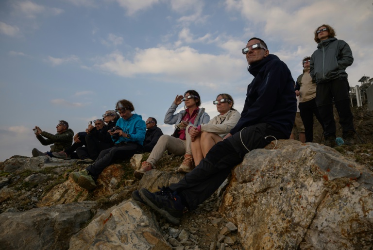 Des personnes observent la Lune passer devant le disque solaire lors d'une éclipse partielle, au sommet du Pic du Midi, le 12 août 2026