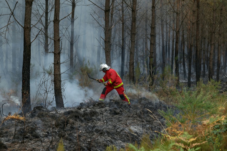Un pompier éteint avec une pelle les débris d'un incendie qui couvent à Marcheprime, à l'ouest de Bordeaux, le 26 juillet 2026