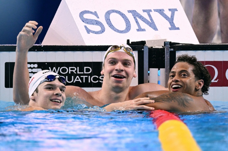Léon Marchand (au centre) à côté de son ami et partenaire d'entraînement Hubert Kos (à gauche), et l'Américain  Shaine Casas après le 200 m 4 nages lors des championnats du monde de Singapour le 31 juillet 2025.