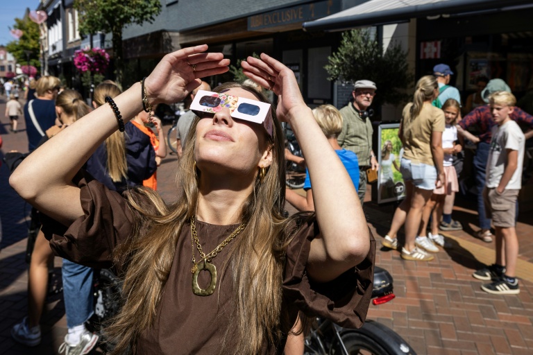 Une femme observe l'éclipse solaire totale avec des lunettes de protection en Espagne.