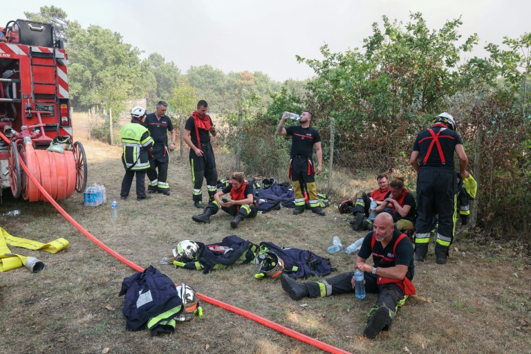 Des pompiers se reposent avec des bouteilles d'eau pendant une pause au cours des opérations de lutte contre un incendie de forêt près de Lanton, dans le sud-ouest de la France, le 29 juillet 2026