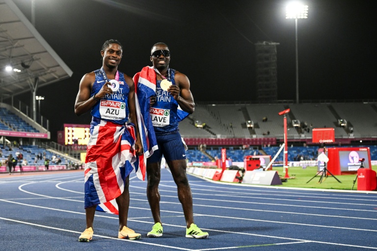 Les Britanniques Jeremiah Azu (g) et Romell Glave fêtent leurs médailles d'argent et d'or respectivement du 100m des championnats d'Europe devant les tribunes dégarnies de l'Alexander Stadium de Birmingham, le 11 août 2026
